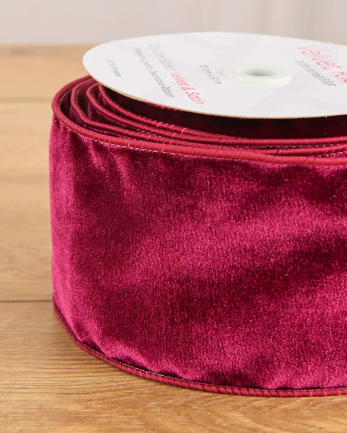 Close-up of the burgundy velvet surface and wired satin edging on the 10 cm ribbon.