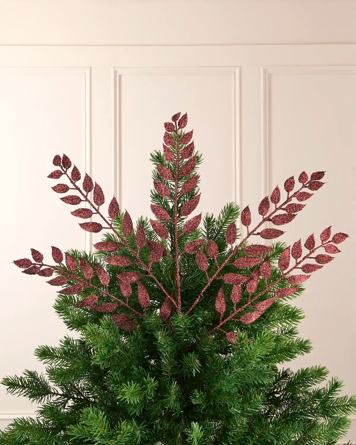 Multiple 73 cm burgundy glitter leaf sprays arranged across the top of a Christmas tree.