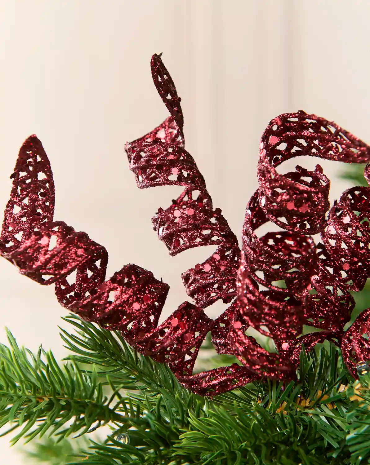 Close-up of burgundy glitter spiral picks showing curled openwork shapes and reflective sequin details.