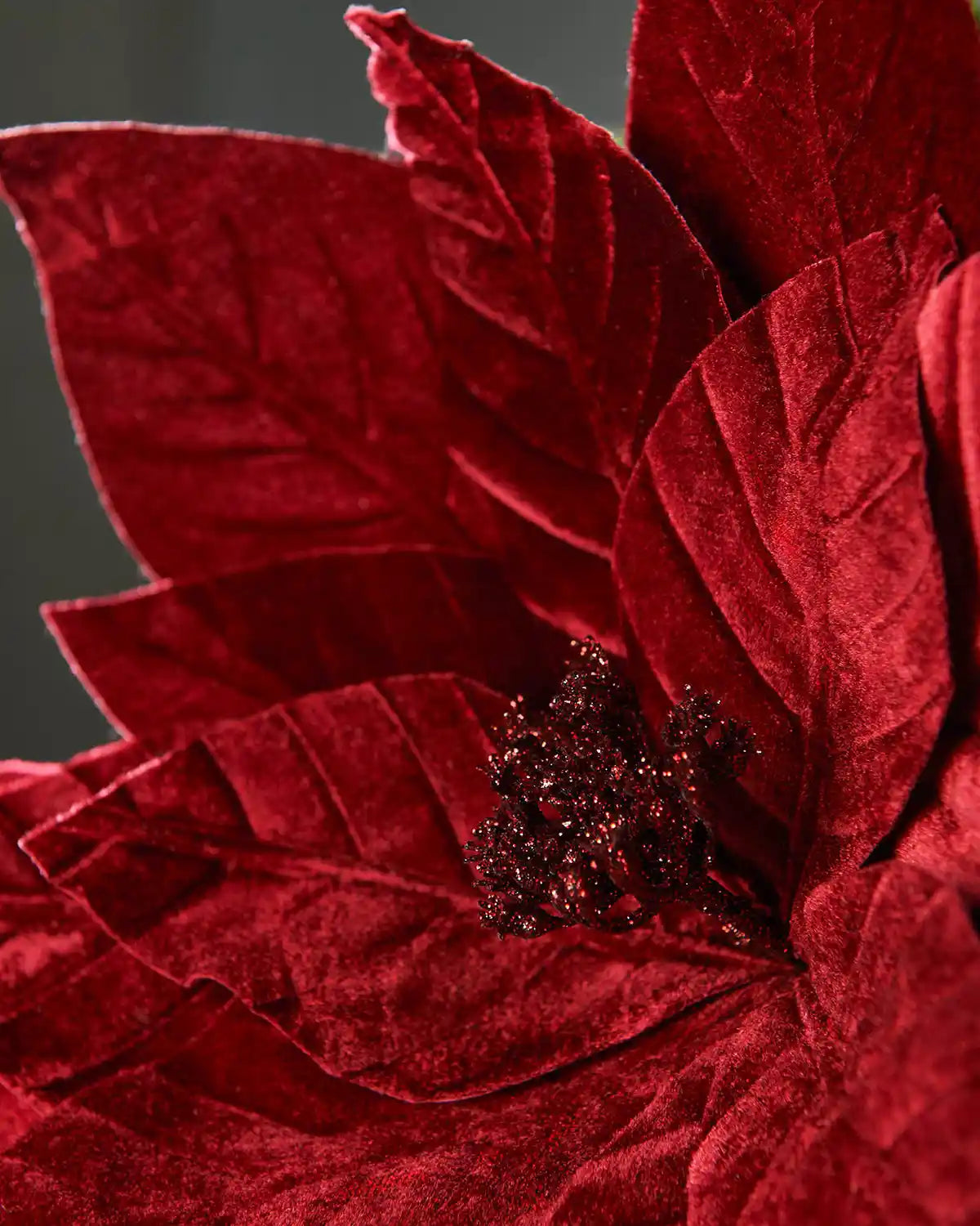 Close-up of a 46 cm burgundy oversized artificial poinsettia flower showing textured velvet-effect petals and a glittered stigma.