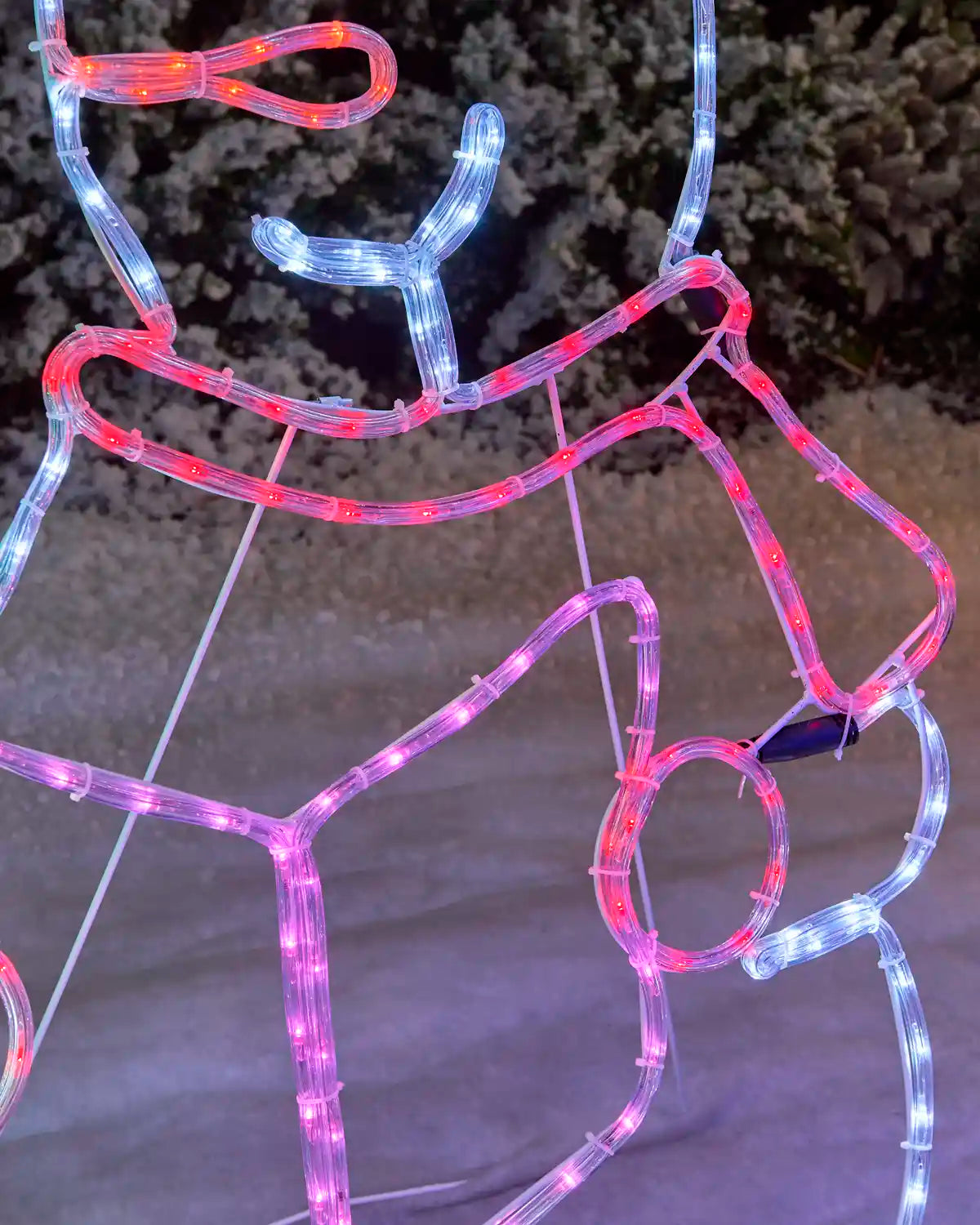Close-up detail of the pre-lit carolling snowmen rope light silhouette showing colorful illuminated rope lights outlining the snowman, scarf, and carol book