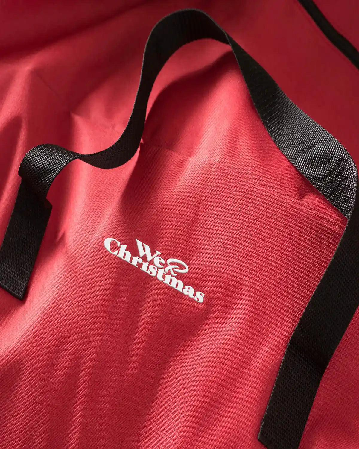 Close-up of the red Christmas tree storage bag with black carry handle and logo