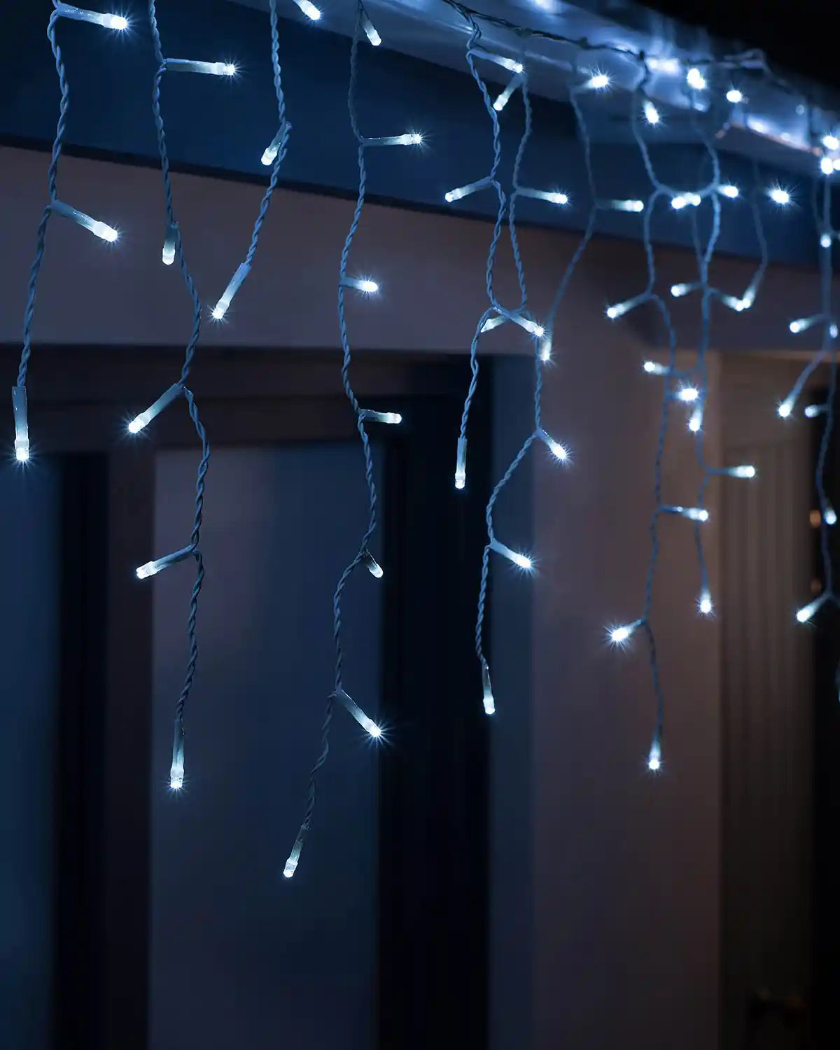 Bright white icicle Christmas lights hanging indoors with glowing LED drops
