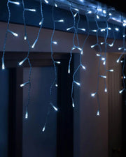 Bright white icicle Christmas lights hanging indoors with glowing LED drops