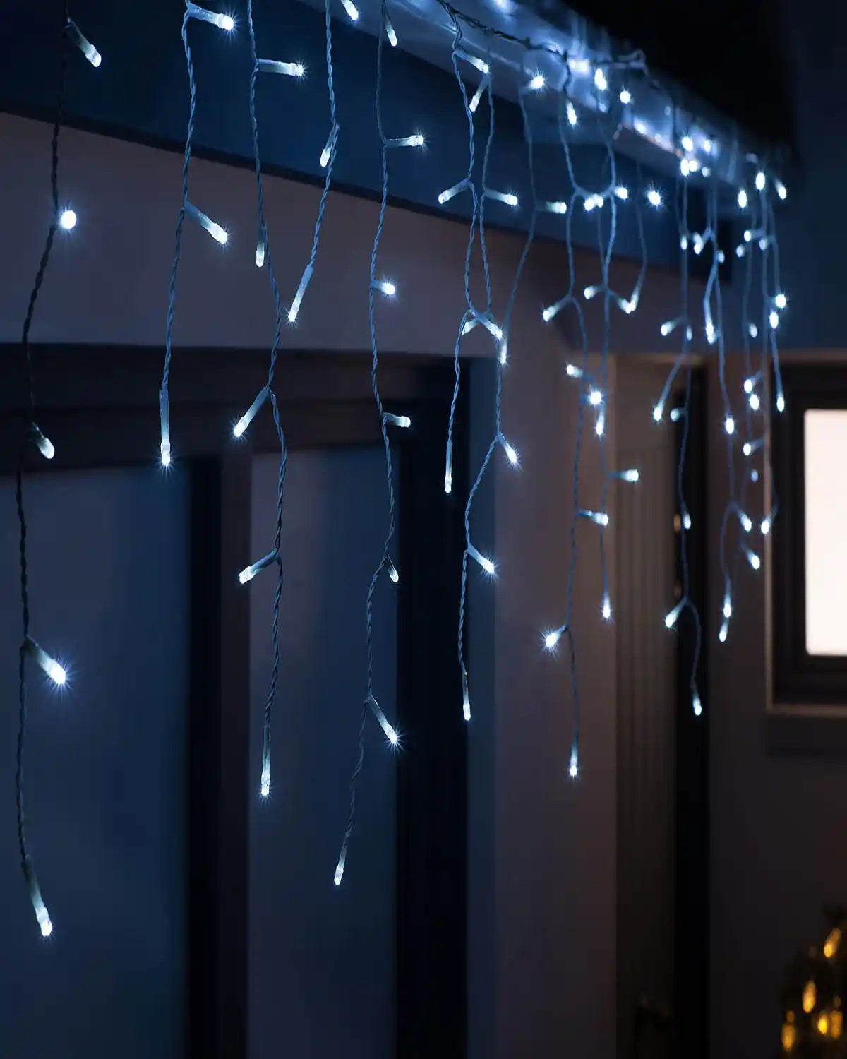 Bright white connectable icicle lights displayed across a window for a festive glow