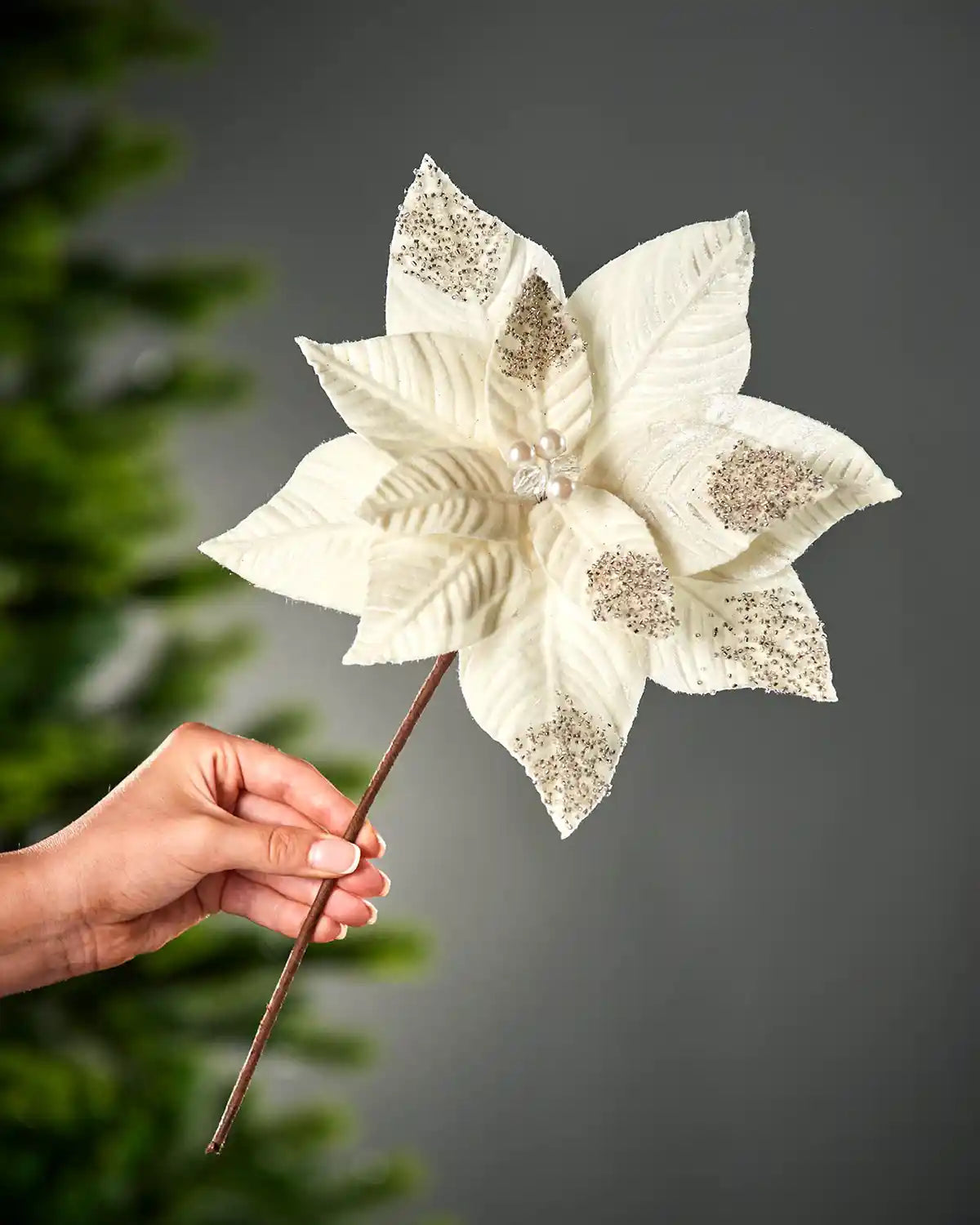 27 cm cream artificial poinsettia flower held by its stem, showing layered petals with beaded accents.