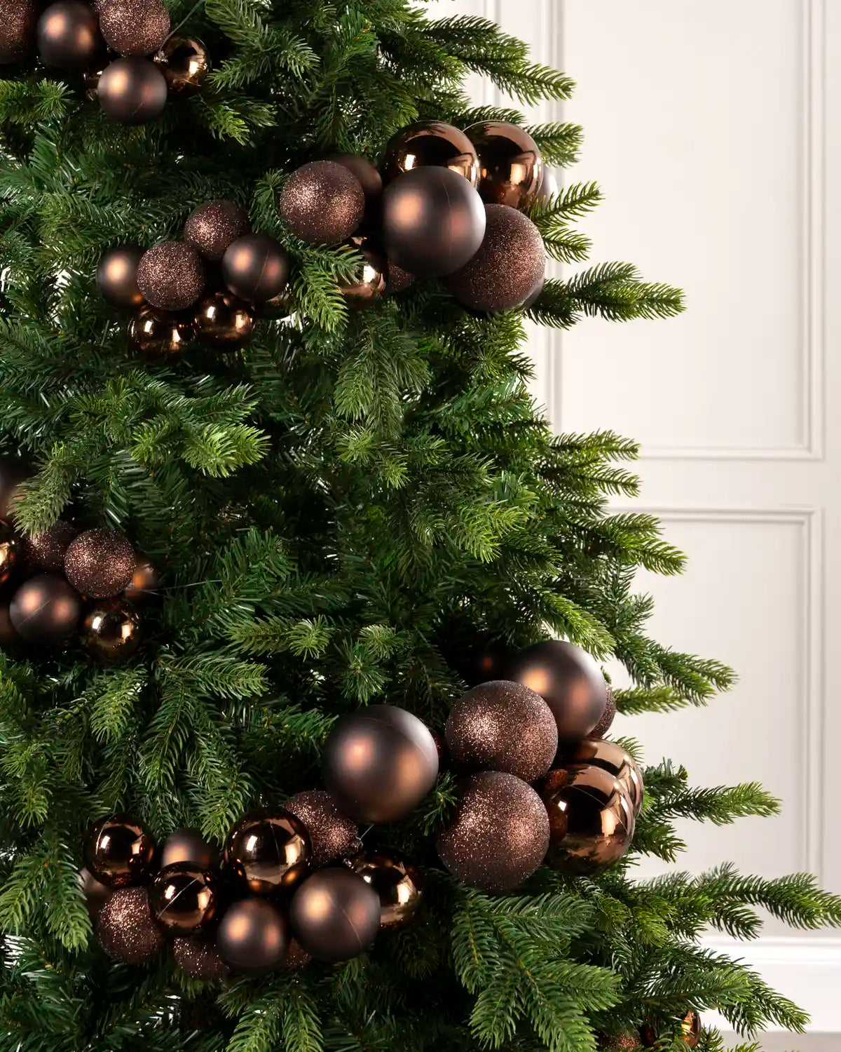 Close-up of espresso bauble cluster arch on a Christmas tree showing mixed sizes and finishes.