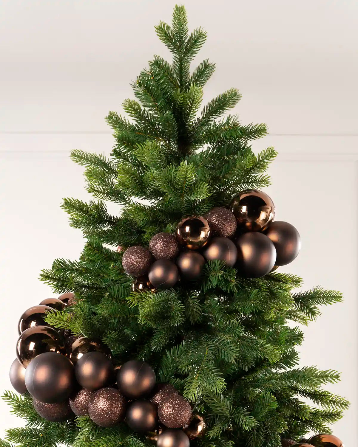 Espresso bauble cluster arch styled through the upper branches of a green Christmas tree.