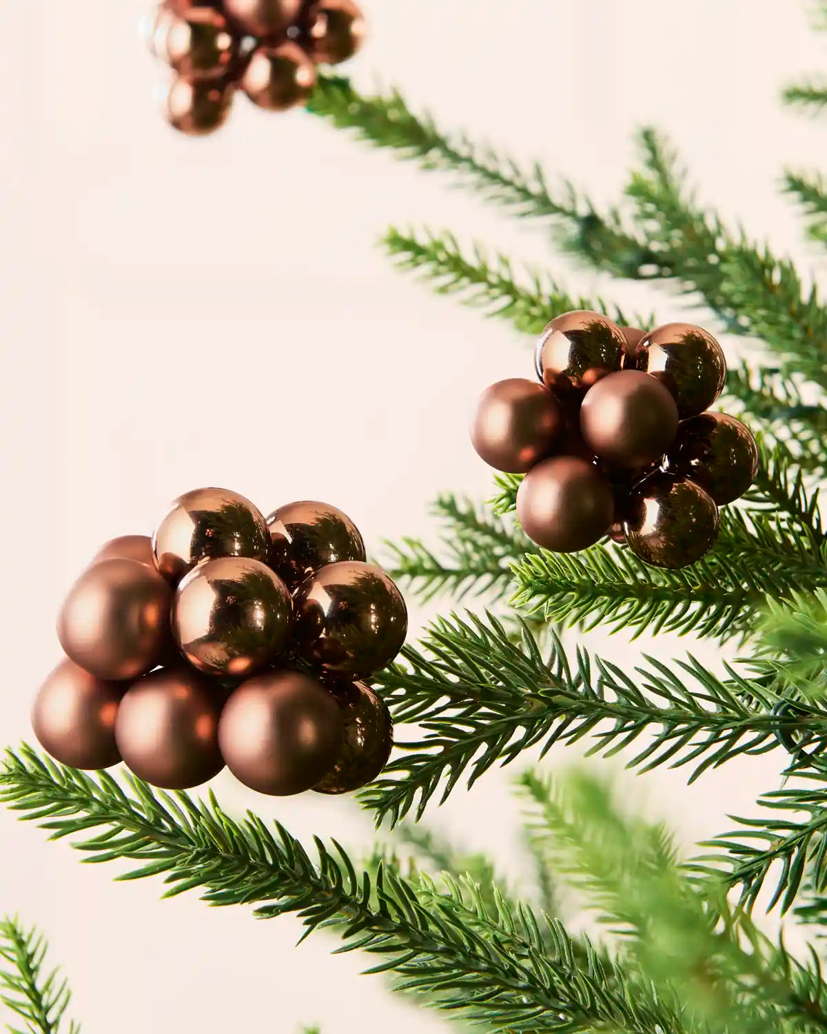 Close-up of espresso glass berry cluster baubles with shiny and matt finishes on a Christmas tree.