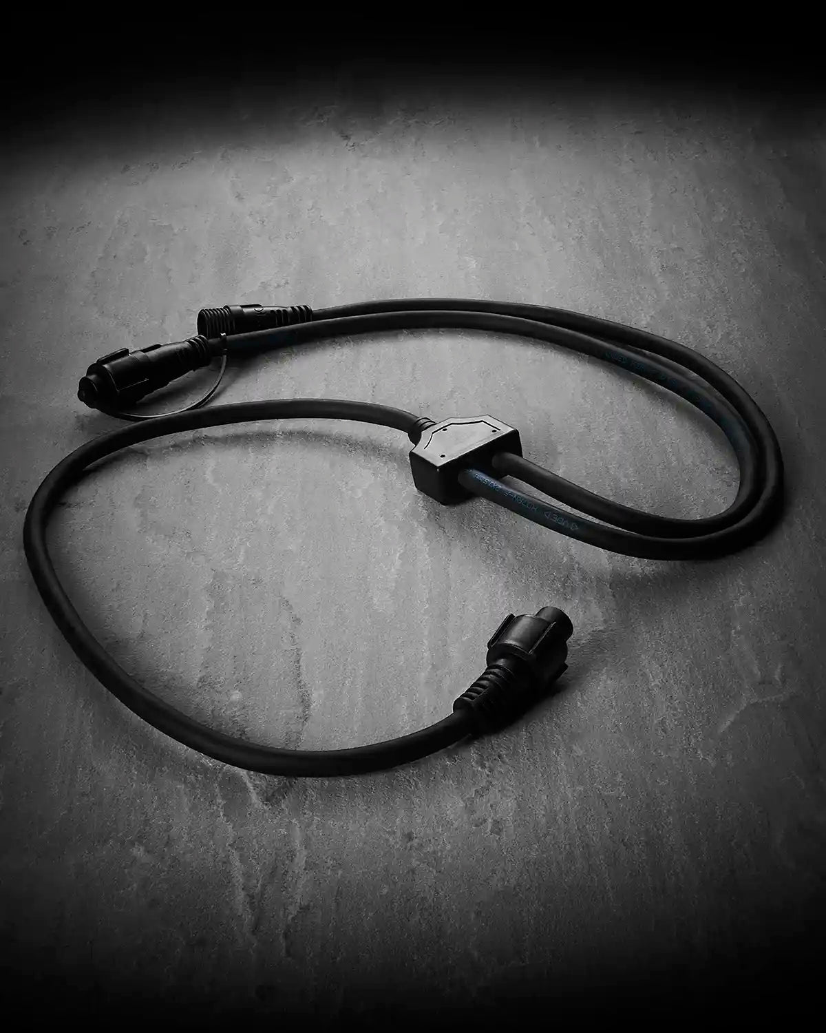 Black Festoon Series connectable Y cord connector on a grey surface.