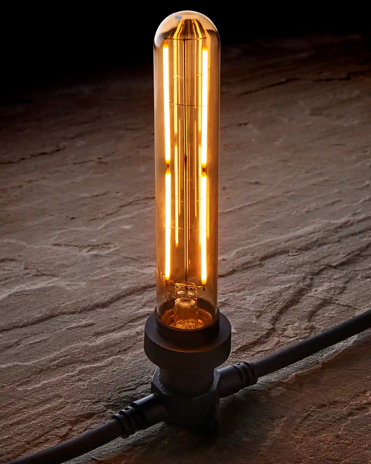 Close-up of a warm white E27 tubular filament bulb with golden-tinted glass fitted into a black festoon belt.
