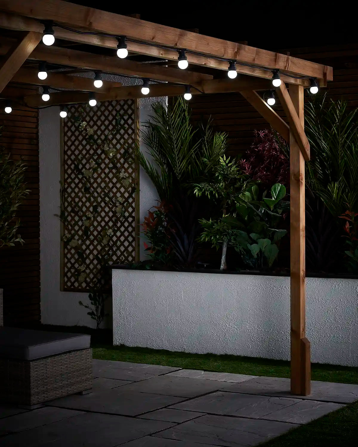 Close-up of white globe festoon bulbs fixed along wooden pergola beams in an outdoor garden setting.