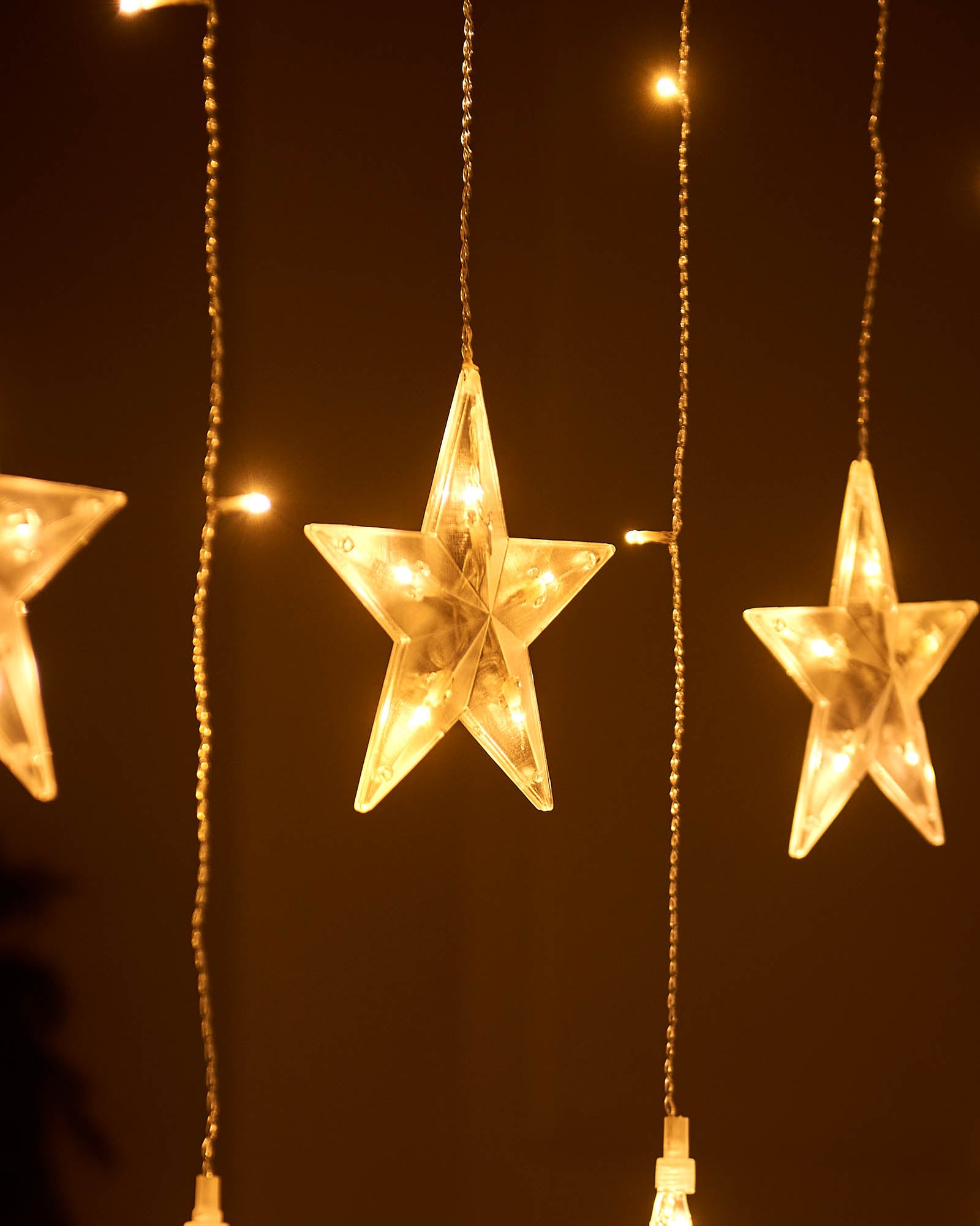 Close-up of warm white star curtain lights with vertical strands and small LED bulbs