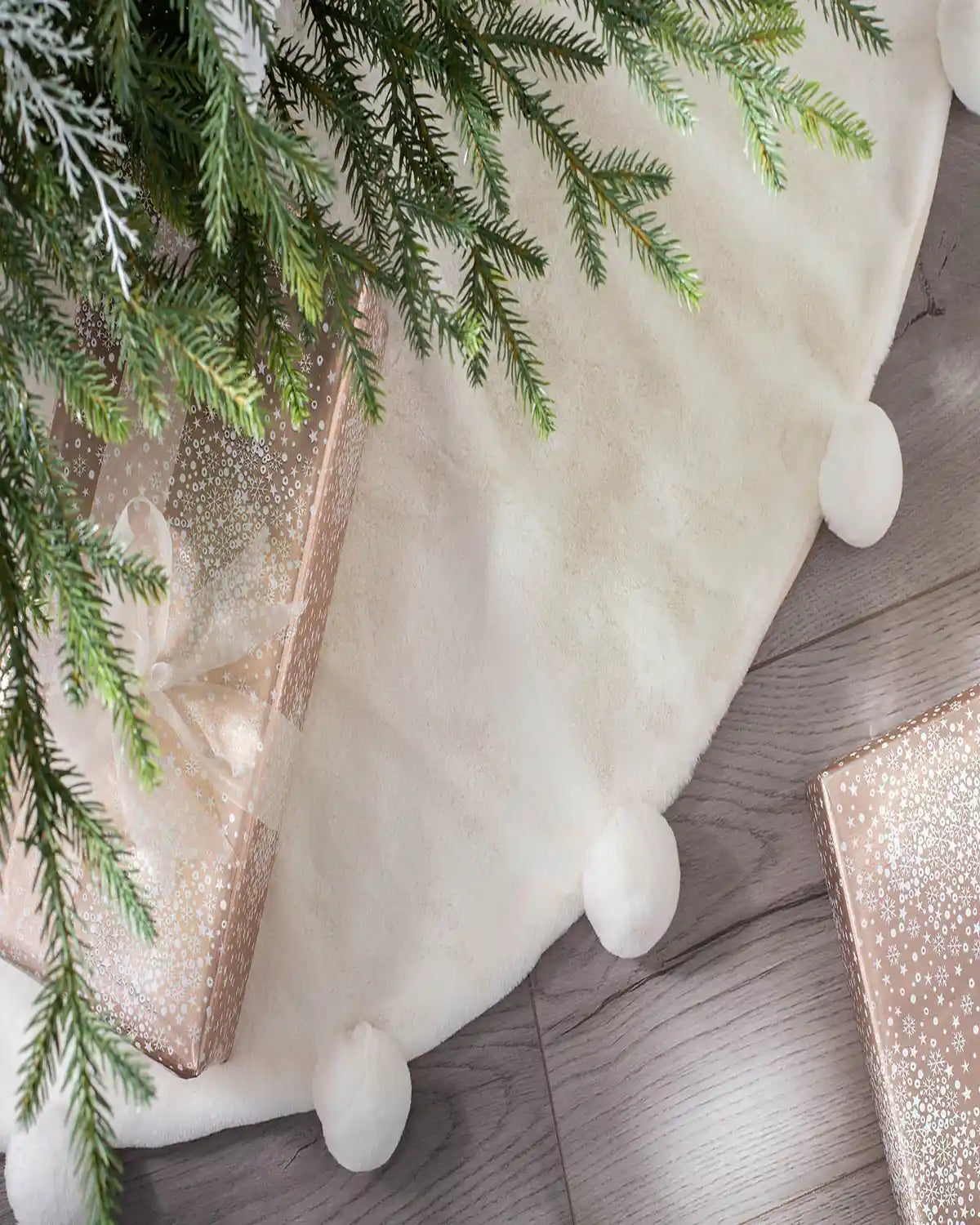 Close-up of cream faux fur Christmas tree skirt with pom pom edging