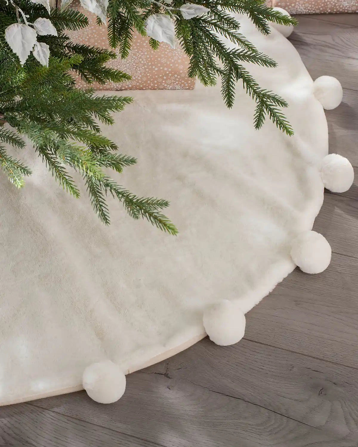 Cream faux fur pom pom tree skirt styled beneath a Christmas tree