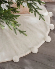 Cream faux fur pom pom tree skirt styled beneath a Christmas tree