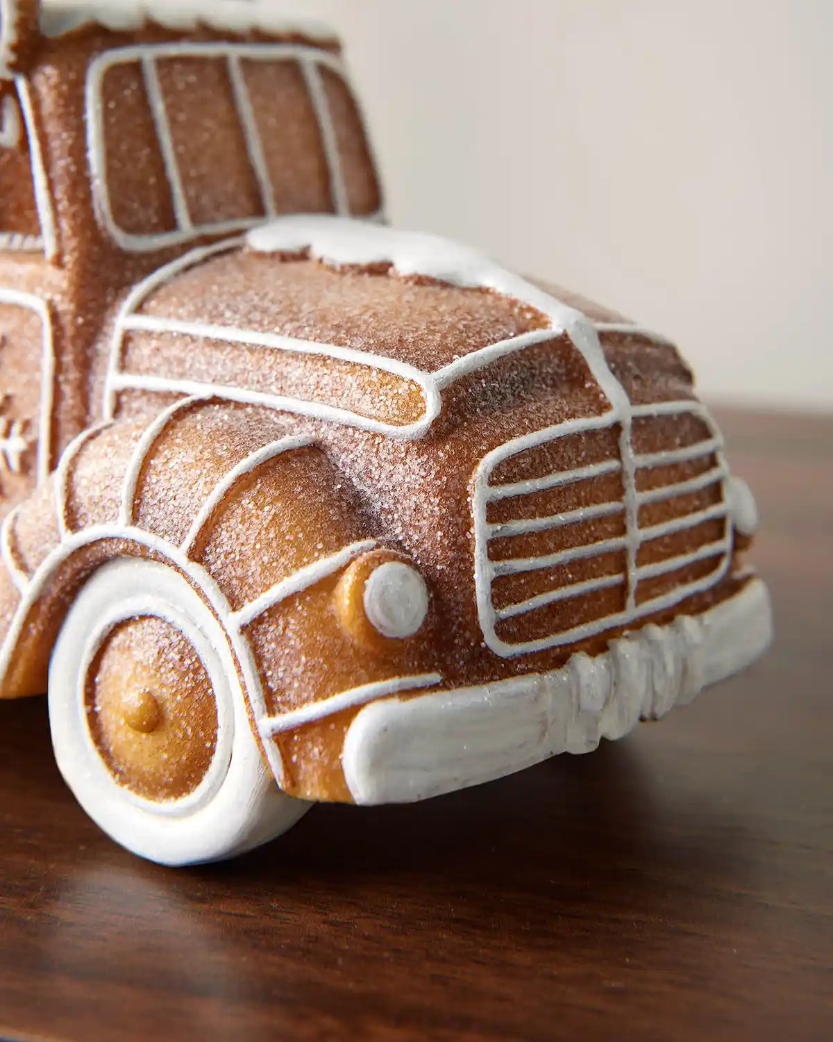 Close-up of the gingerbread car decoration showing the front bonnet, grille, wheel and white icing-style lines.