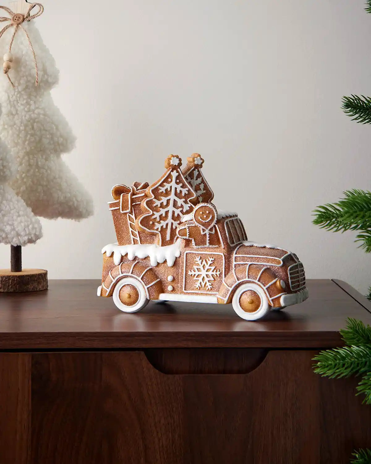 21cm gingerbread car decoration displayed on a wooden mantelpiece with festive tree décor nearby.