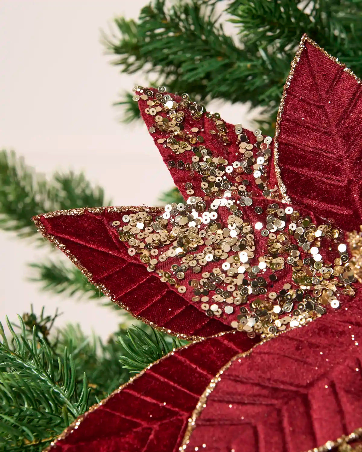 Detailed close-up of a Burgundy & Gold artificial poinsettia flower, showing its glittered Burgundy petals and sparkling gold sequin-covered center
