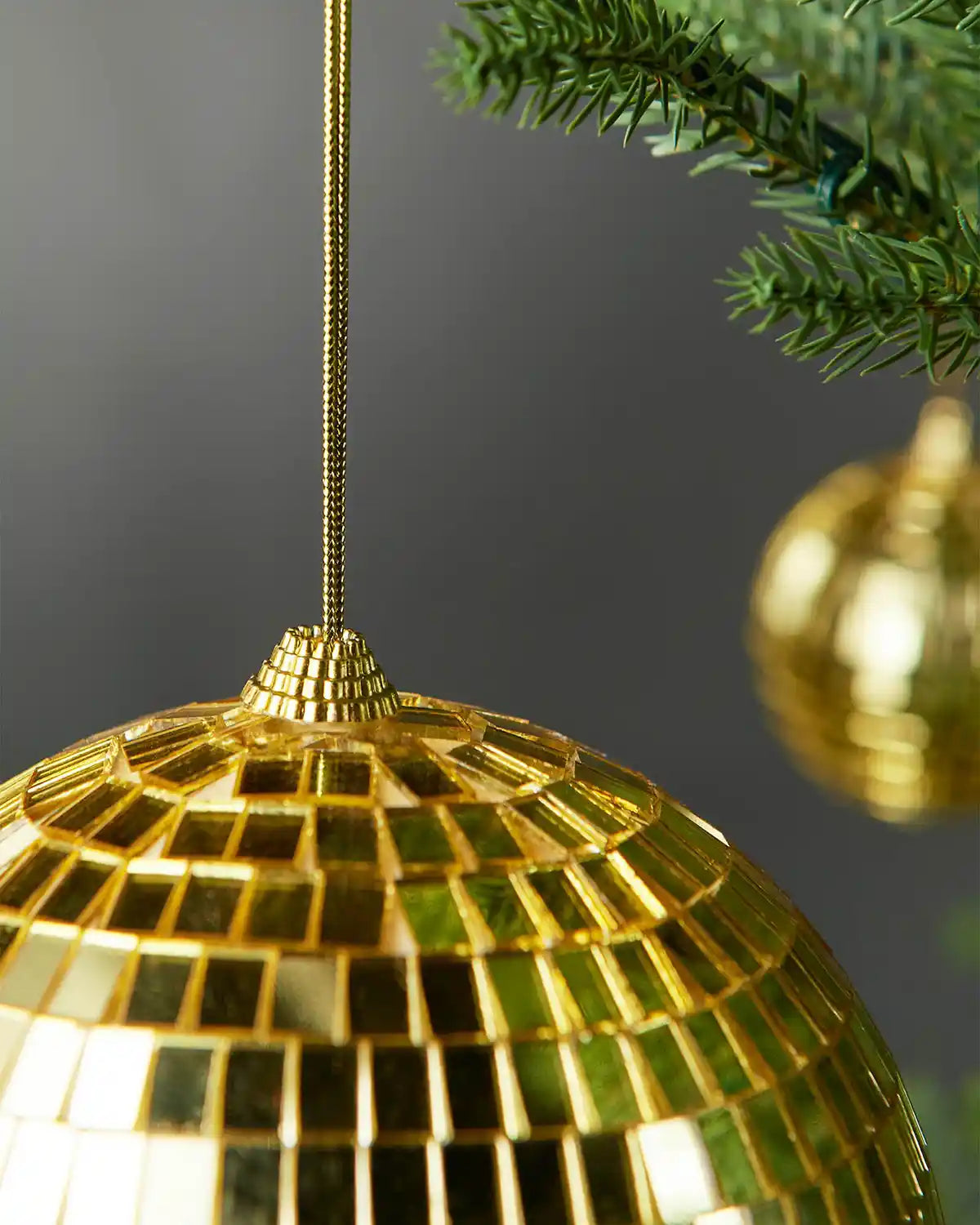 Detailed view of the hanging string and mirrored surface on a gold 15cm disco ball bauble.