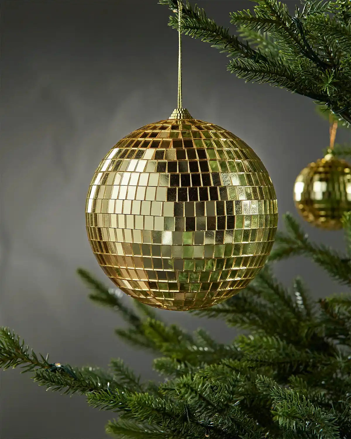 Gold 15cm oversized disco ball bauble hanging on a Christmas tree.