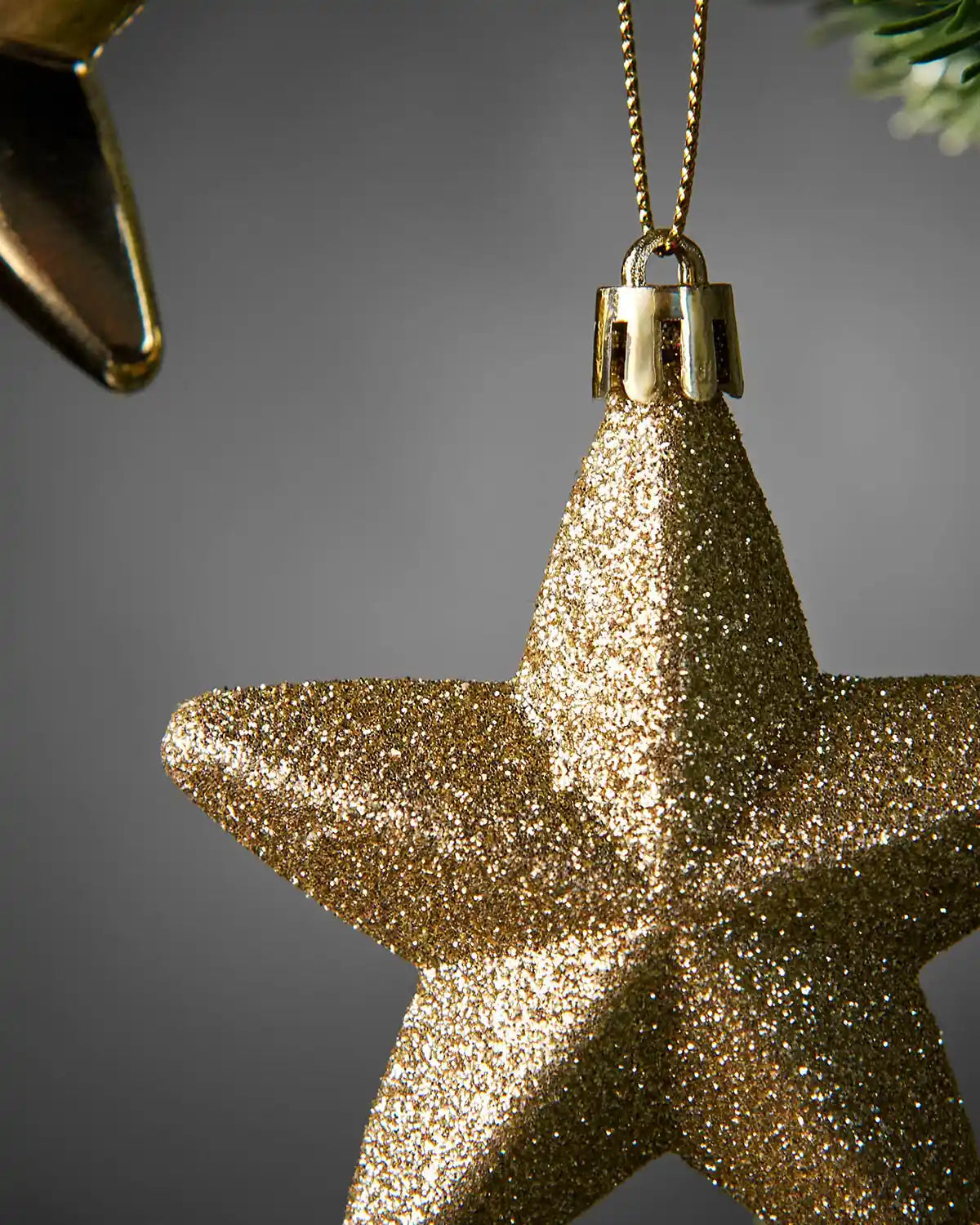 Detailed close-up of a gold 7cm glitter hanging star showing the textured finish and gold cap.