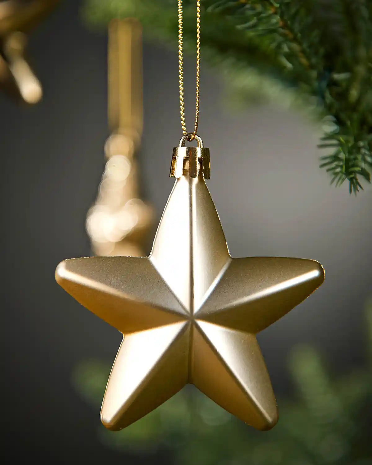 Close-up of a matte gold 7cm hanging star with gold string.