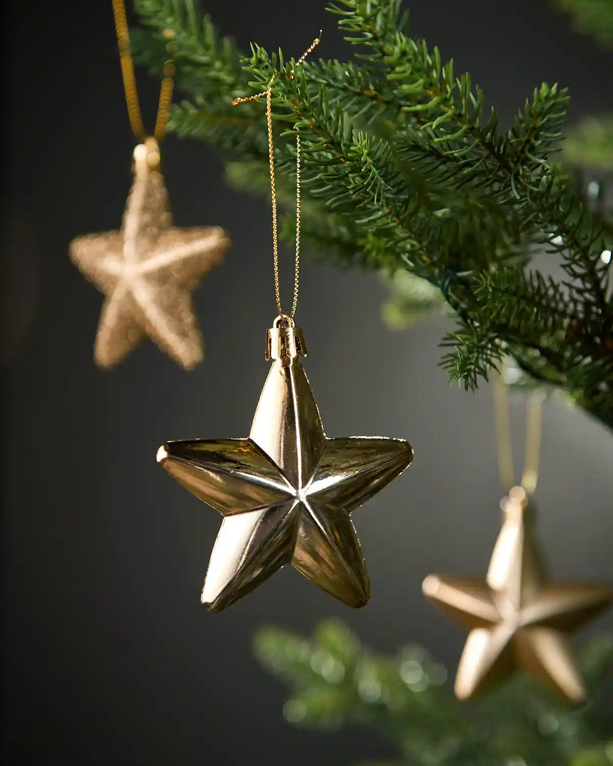 Close-up of a shiny gold 7cm hanging star with gold string on a Christmas tree.