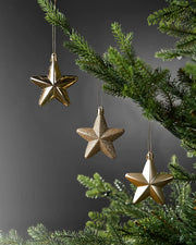 Gold 7cm hanging star decorations in shiny, glitter and matte finishes displayed on a Christmas tree.