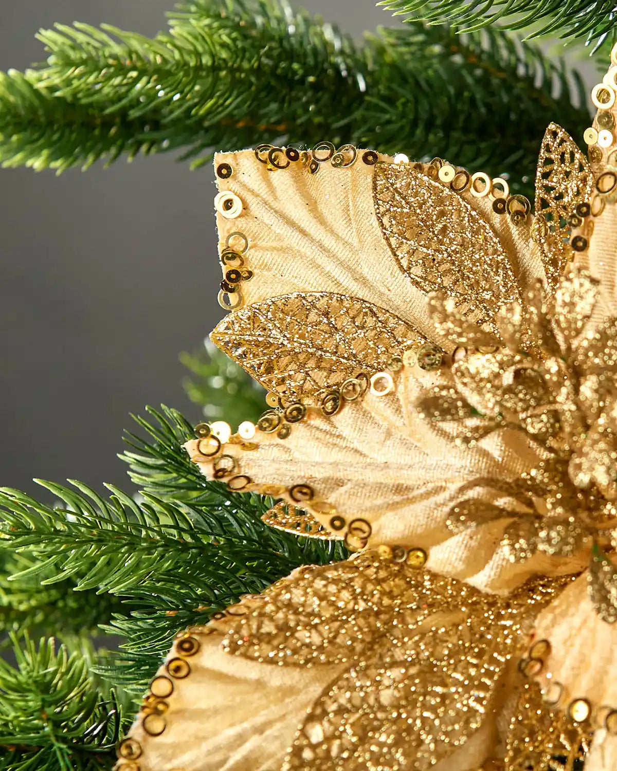 Close-up of a gold artificial poinsettia showing sequin trim, glittered lace detail and textured petals.
