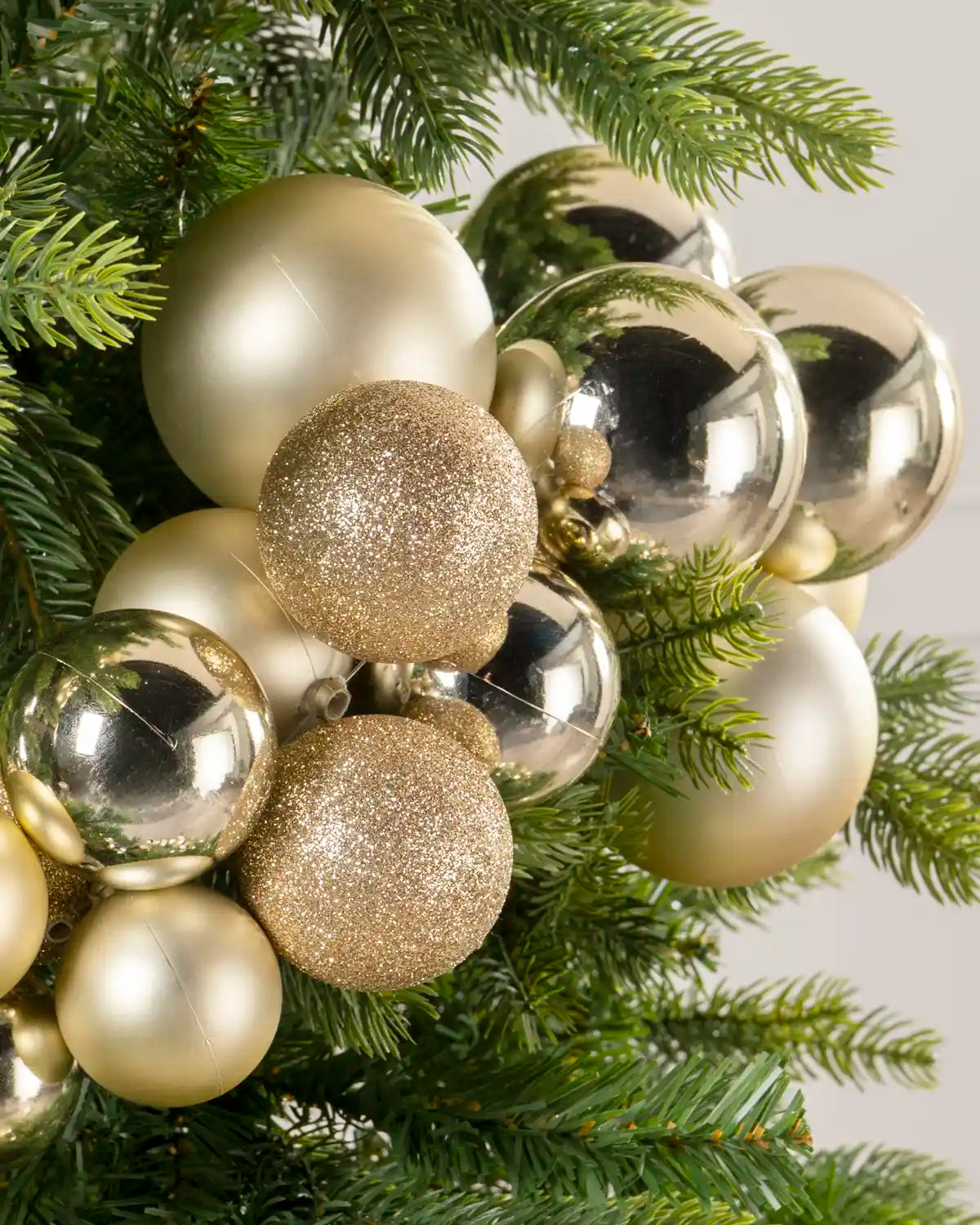 Gold bauble cluster arch arranged through the upper branches of a green Christmas tree.