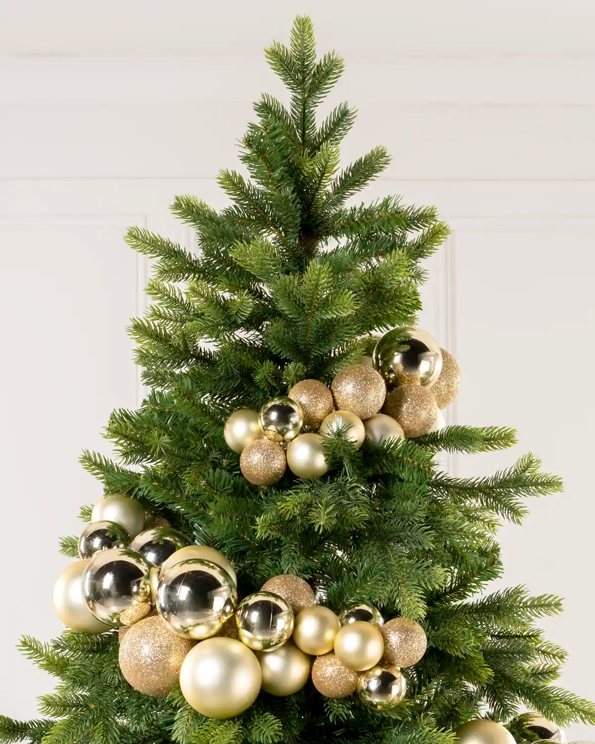 Close-up of gold baubles showing shiny, matt and glitter finishes on a Christmas tree.