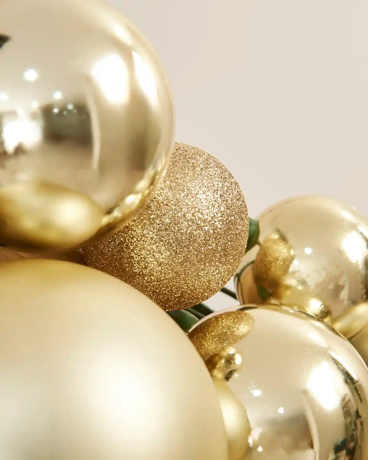 Detailed close-up of glitter, shiny and matt gold baubles within the garland.