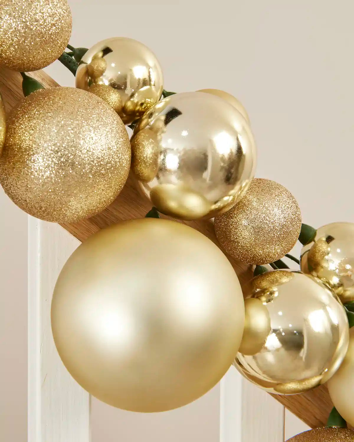 Close-up of gold baubles in shiny, matt and glitter finishes arranged along a staircase.