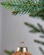 Gold bauble ornament hook attached to a Christmas tree branch