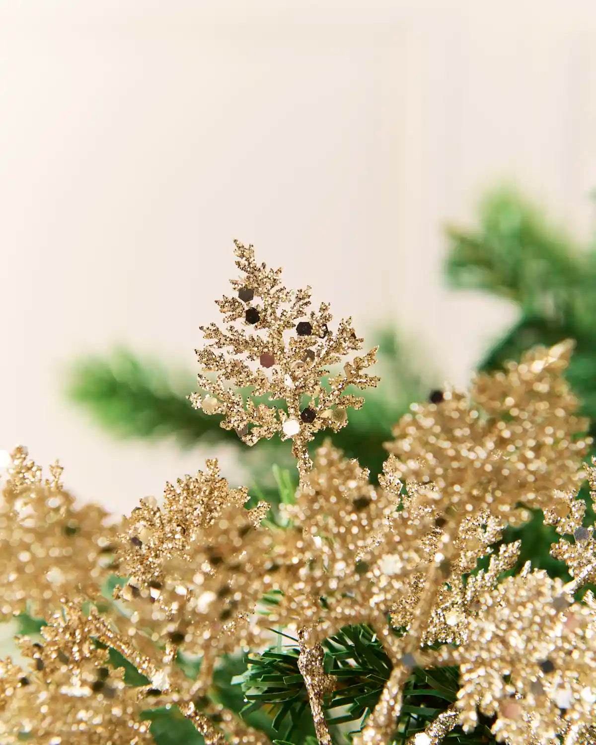 Gold glitter leaf picks grouped together on a Christmas tree with layered metallic leaves.