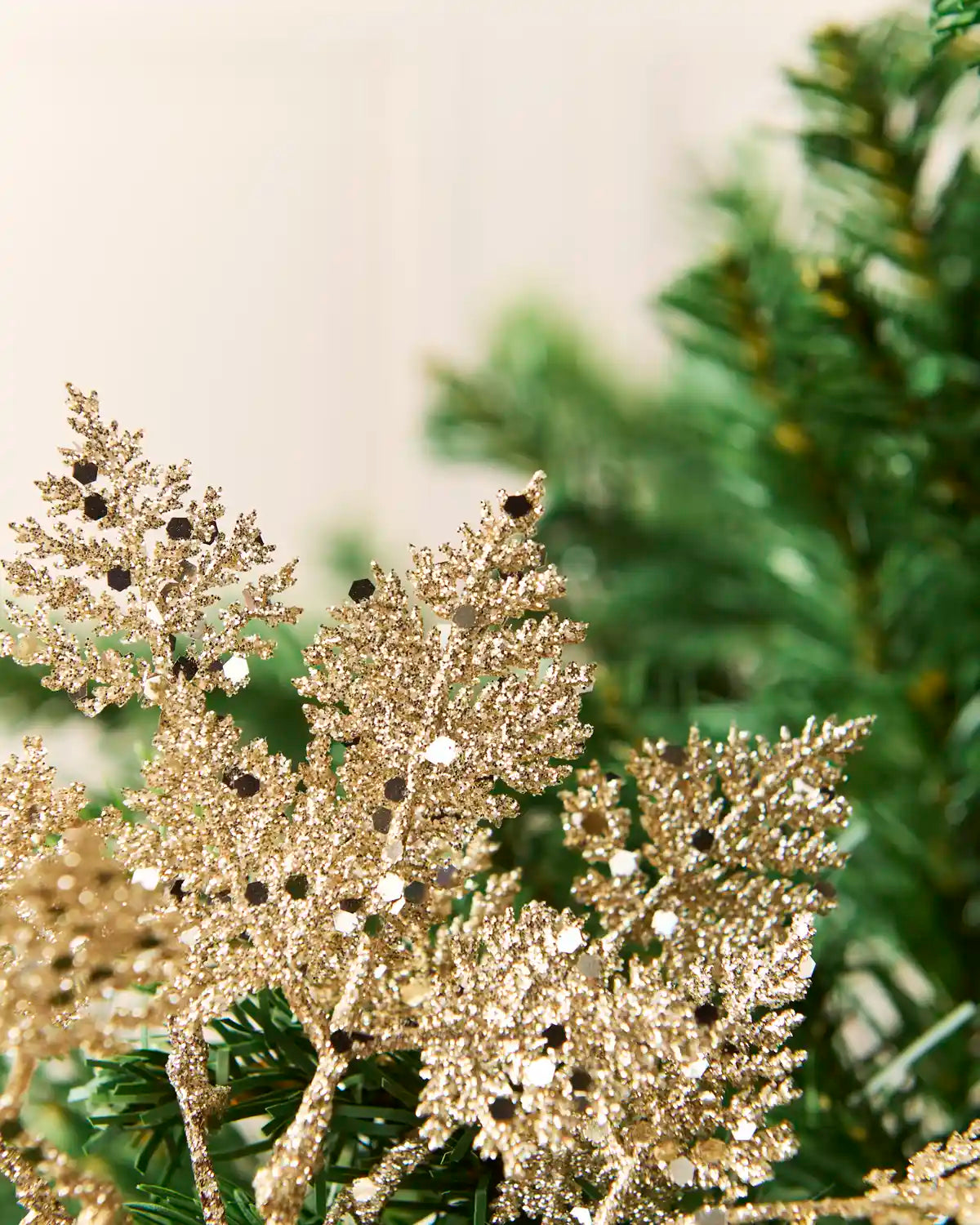Close-up of gold glitter leaves with reflective hexagonal sequins and textured branching edges.