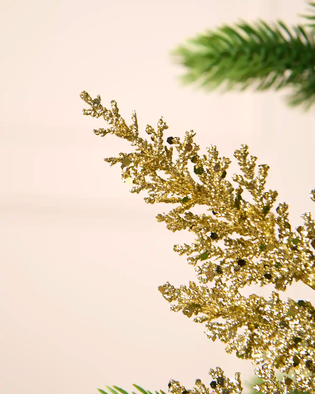 Close-up of gold glitter leaf foliage with scattered reflective sequins and a textured sparkling finish.