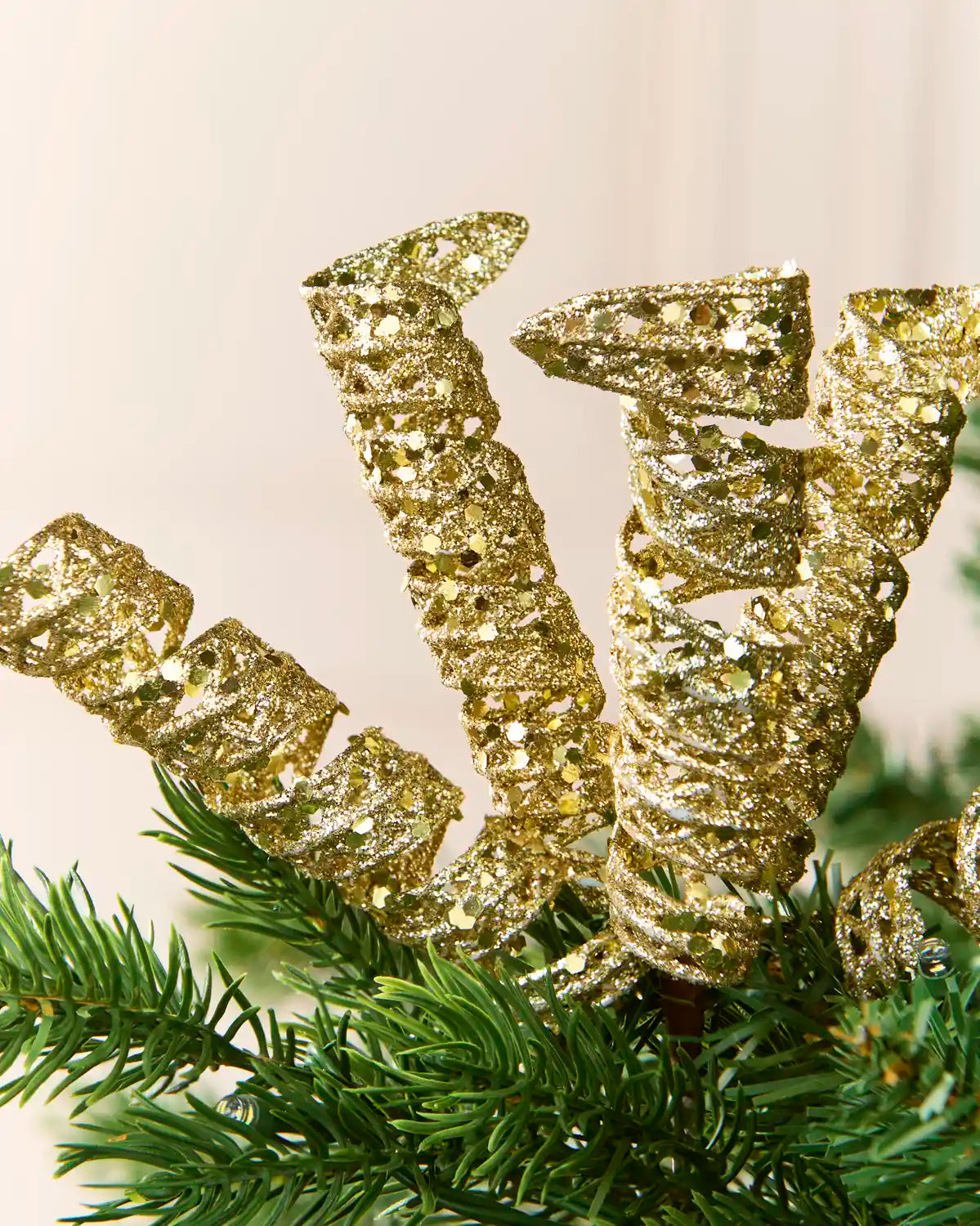 Detailed view of a gold glitter spiral pick showing its curled shape and textured reflective finish.