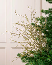 Gold 90 cm glitter twig tree topper with branching stems displayed among Christmas tree branches.