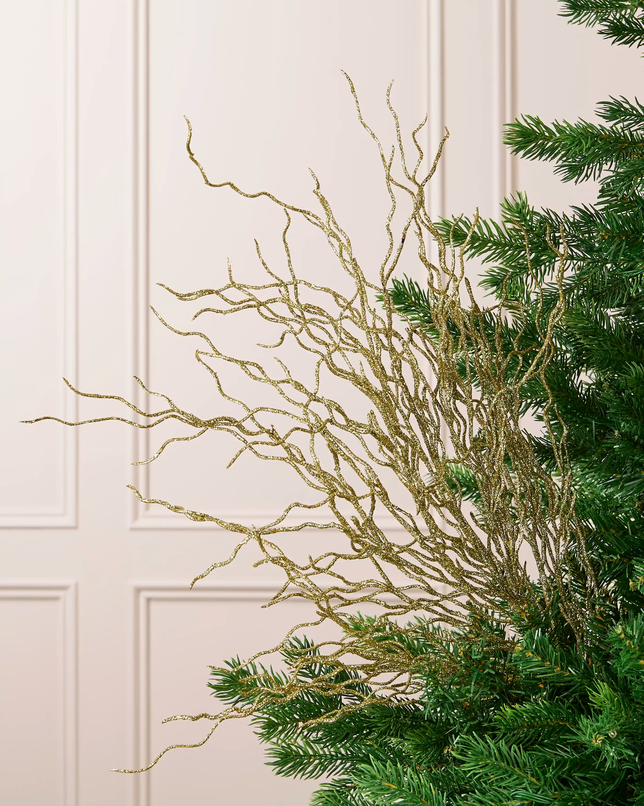 Gold 90 cm glitter twig tree topper with branching stems displayed among Christmas tree branches.