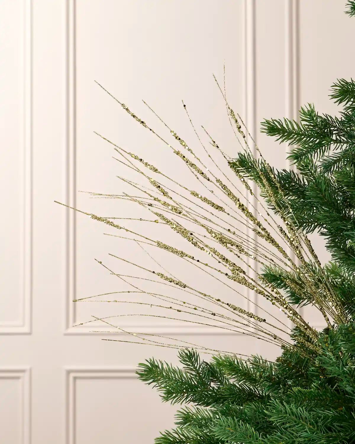 Gold 100 cm glitter wispy spray with fine sequin-accented strands arranged through an artificial Christmas tree.