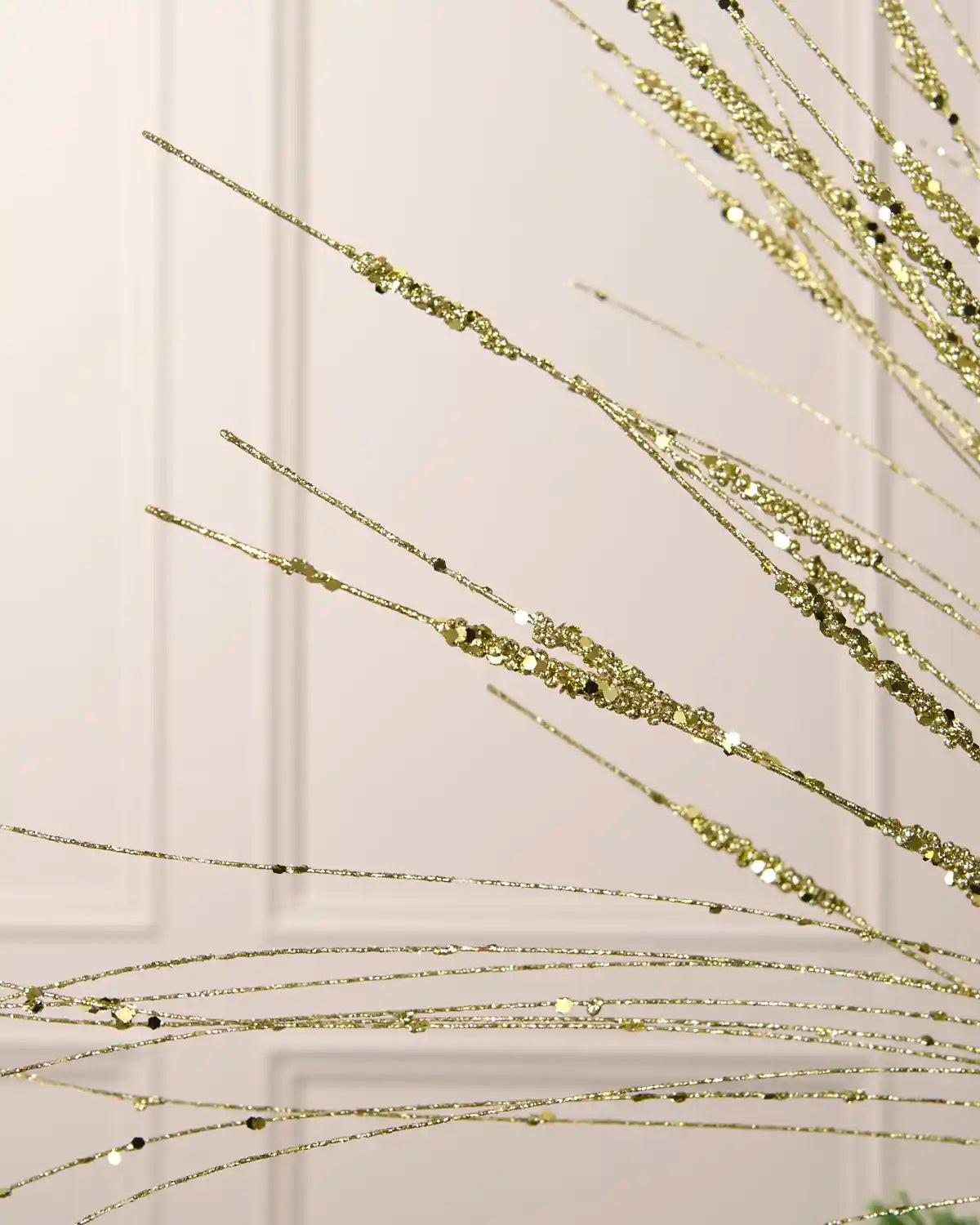 Detailed close-up of fine gold glitter wispy spray strands with reflective sequin accents for Christmas arrangements.