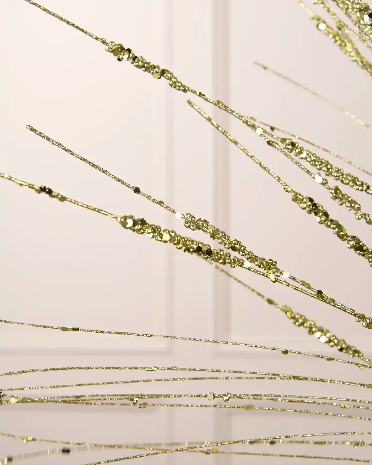 Close-up of the gold glitter and sequin-covered strands on the 100 cm wispy Christmas decoration spray.
