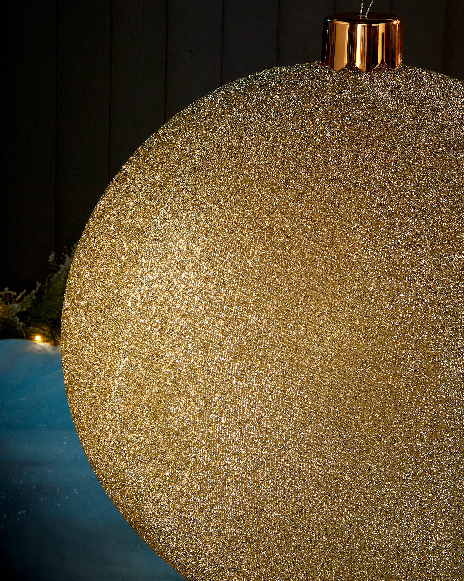 Detail close-up of the textured gold tinsel surface on an inflatable Christmas bauble.