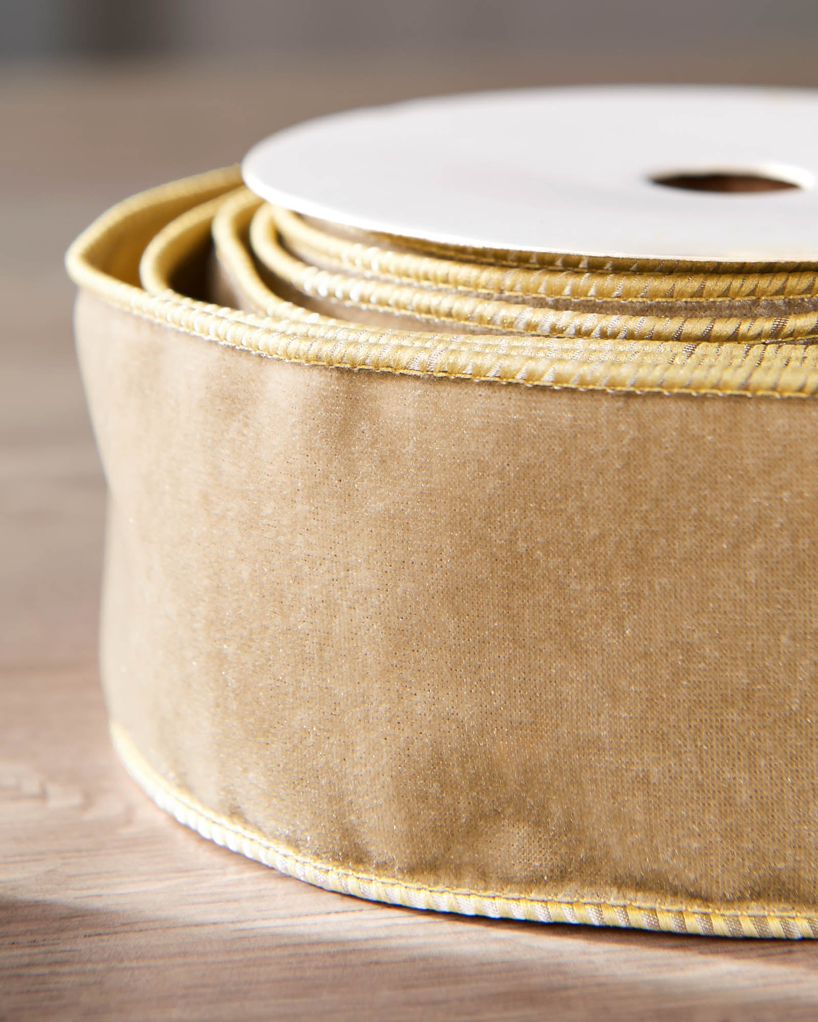 Close-up of gold velvet ribbon on a roll, showing the soft texture and wired edge.