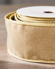 Close-up of gold velvet ribbon on a roll, showing the soft texture and wired edge.