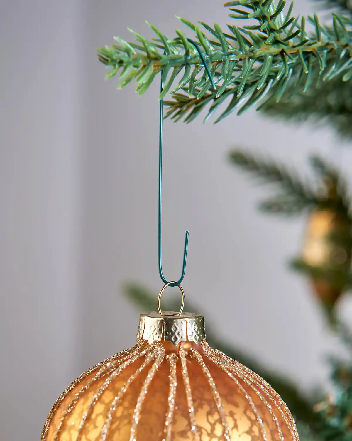 Green bauble ornament hook attached to a Christmas tree branch
