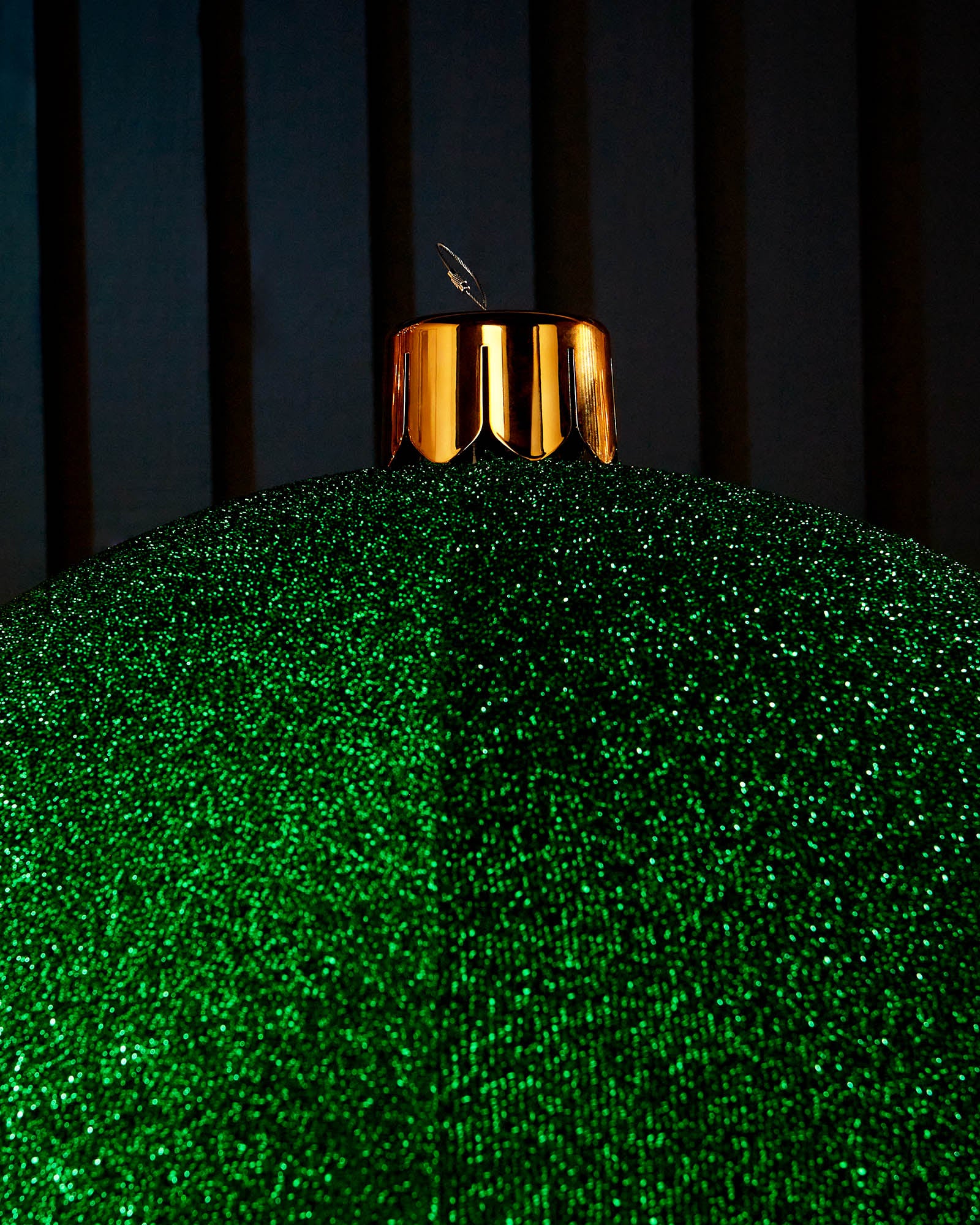 Close-up of the gold cap and hanging wire on a green inflatable tinsel Christmas bauble.