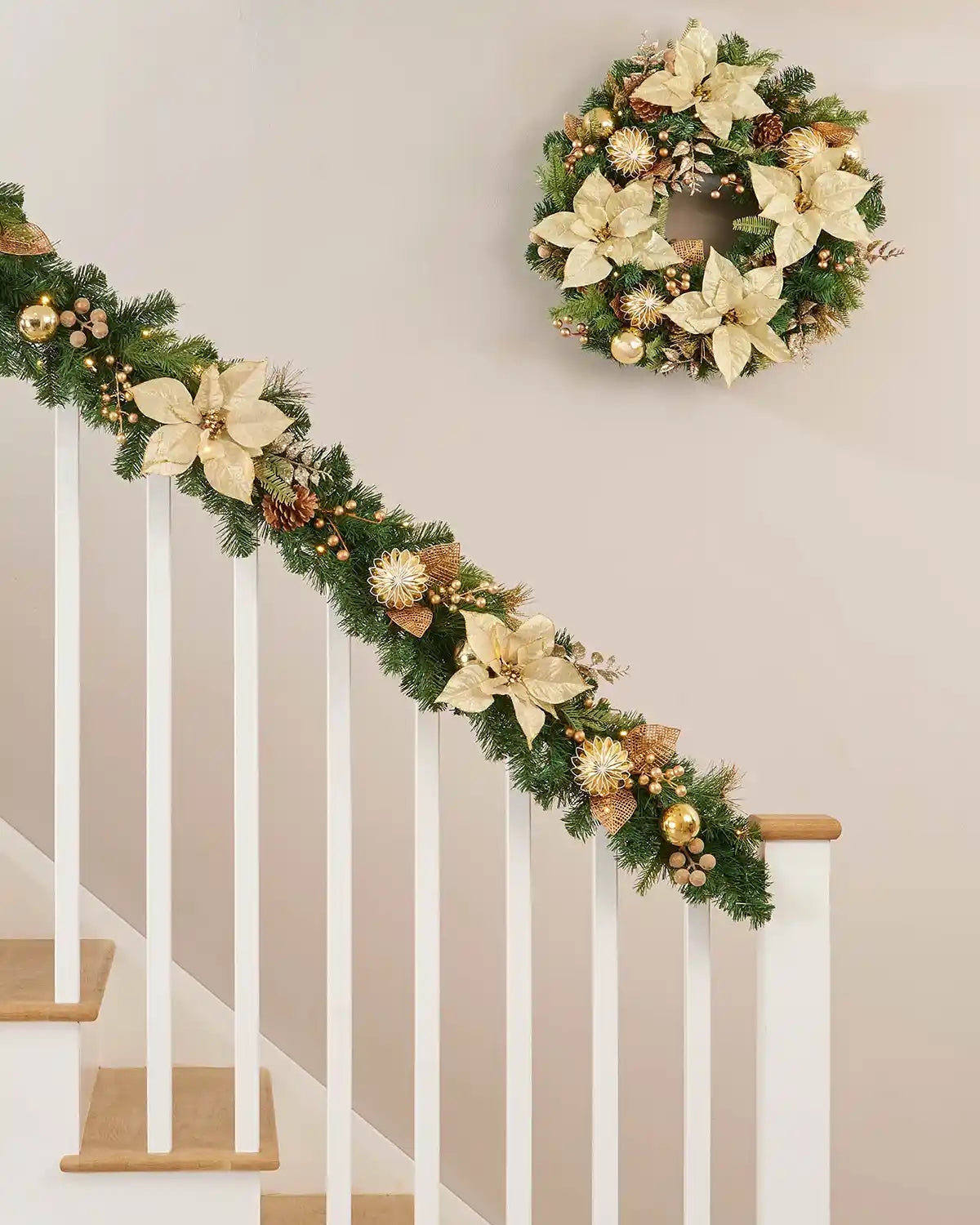 Green garland with pinecone and gold foliage draped on a white wooden staircase